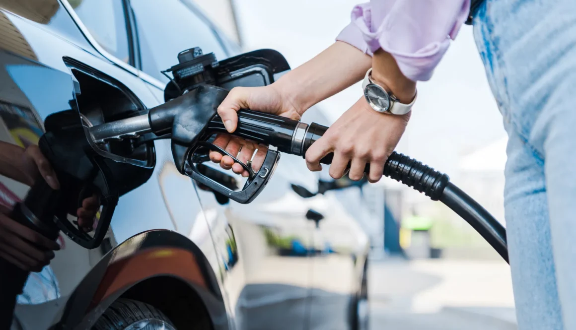 cropped view of woman holding fuel pump while refueling car with benzine