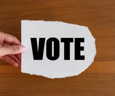 Vote - close up text on the slip. Woman hand holds a piece of paper with text.
