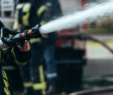 partial view of firefighter with water hose extinguishing fire on street