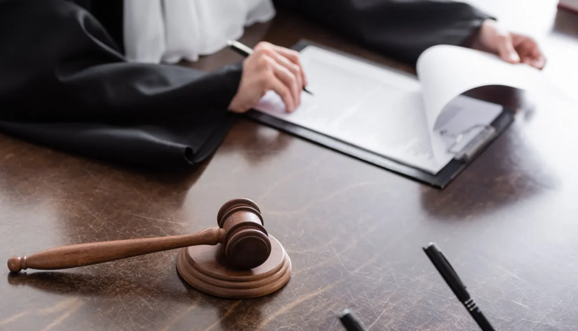 selective focus of wooden gavel near cropped judge and clipboard with verdict