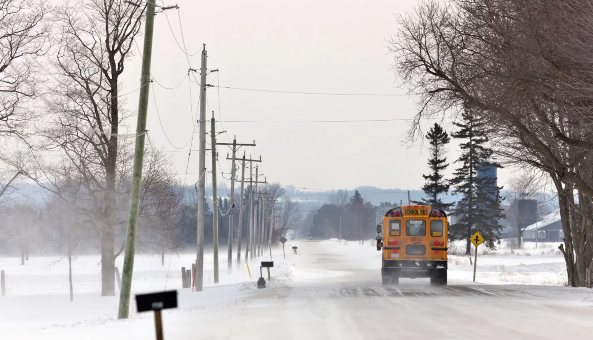 School Bus Travelling Down a Country Road with Snowdrifts and Blowing Snow in Winter. High quality photo