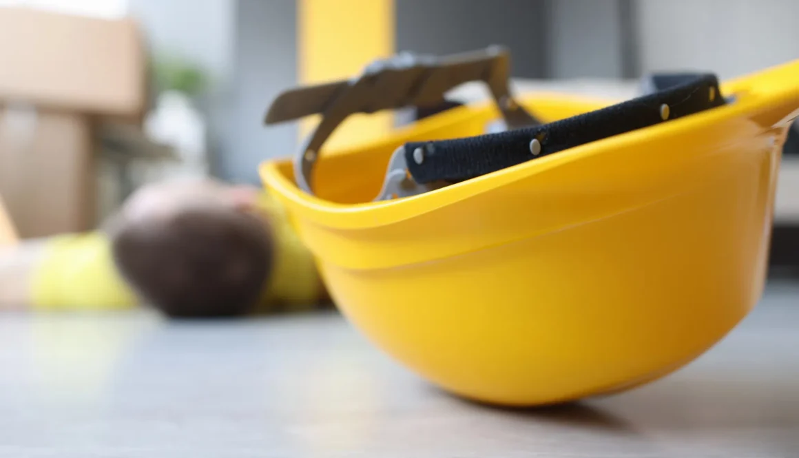 Yellow worker helmet on floor beside motionless construction worker