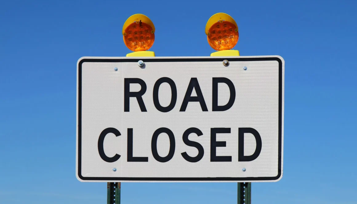Road closed sign against a bright blue sky