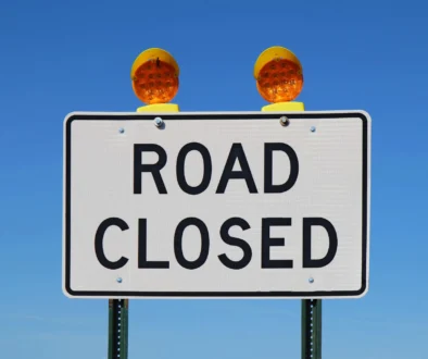 Road closed sign against a bright blue sky