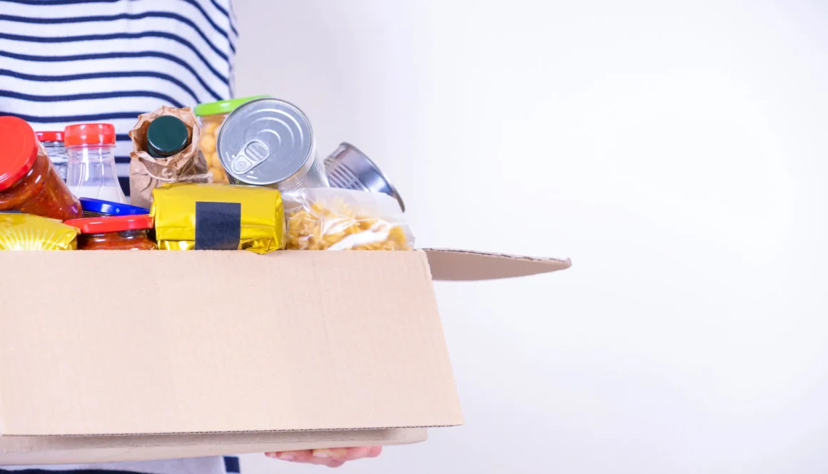 Woman hands holding food donations box with grocery products