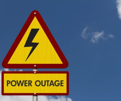Power Outage message on yellow warning road sign with sky