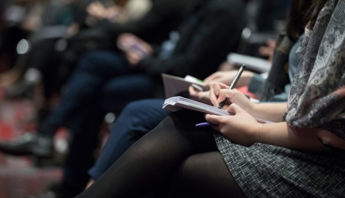 selective focus photography of people sitting on chairs while writing on notebooks