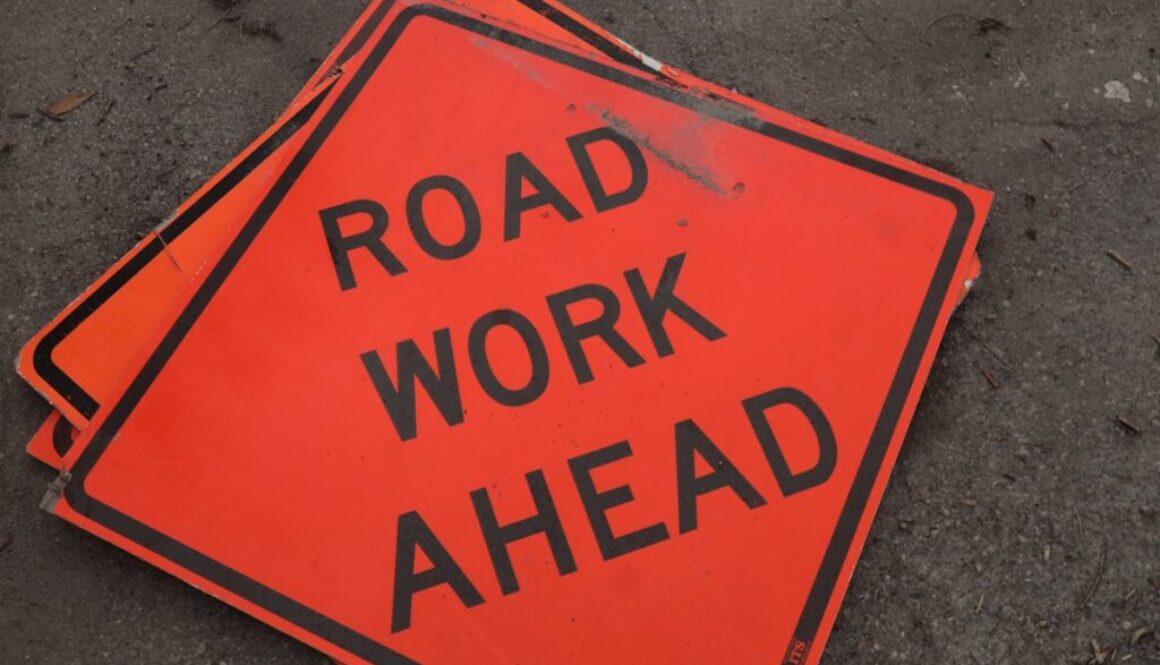 A road work ahead sign laying on the ground
