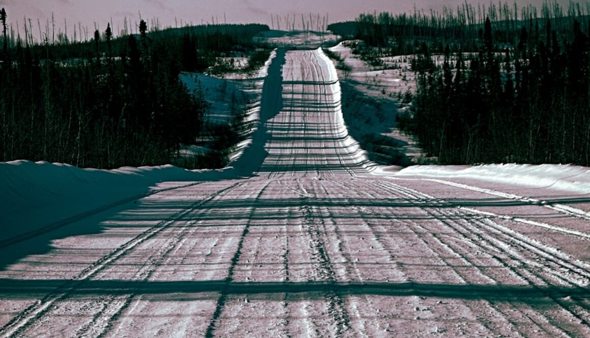 a snow covered road in the middle of a field