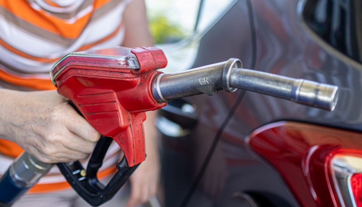 a woman filling a car with gas at a gas station