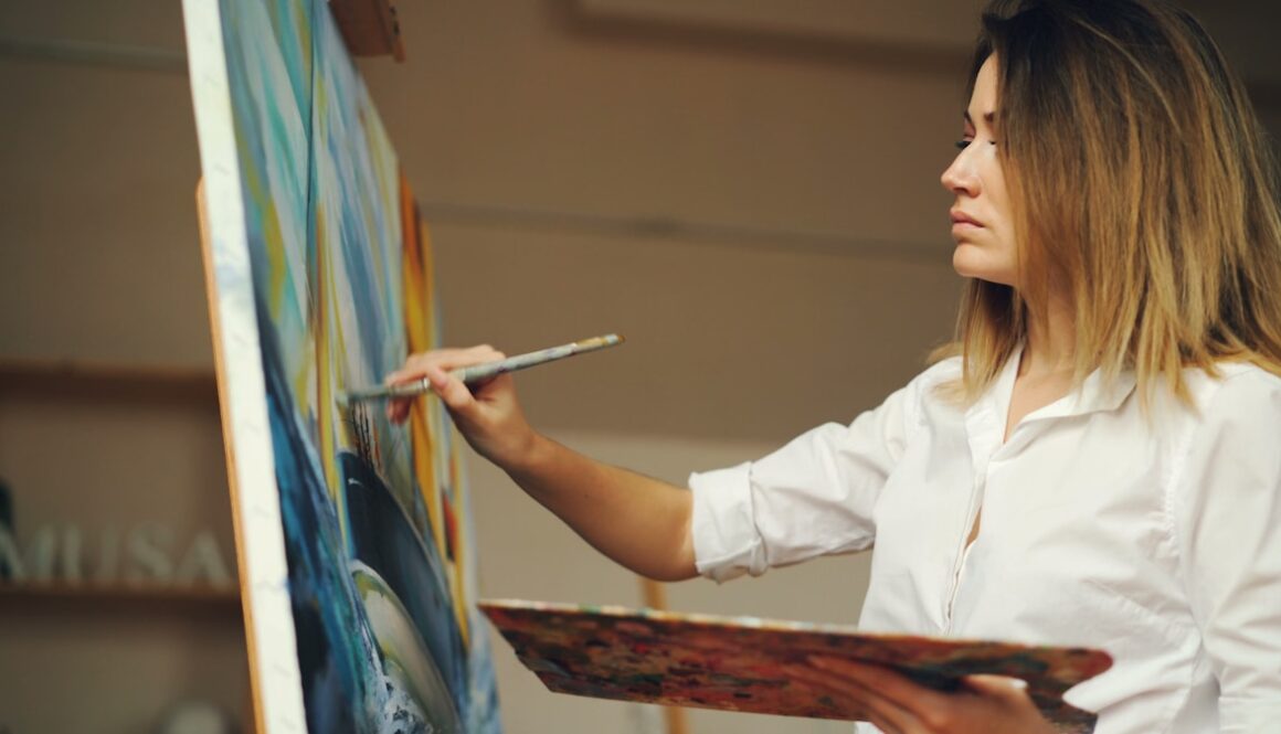 A woman is painting a blue and yellow artwork.