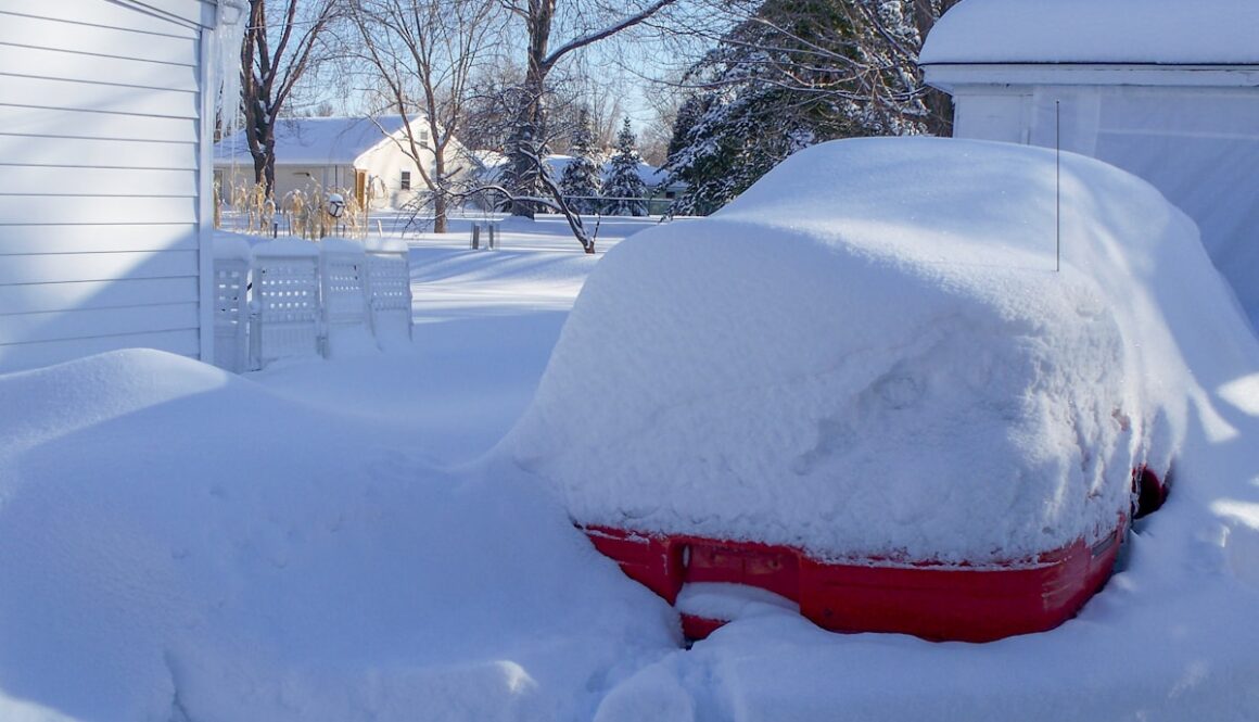a car covered in snow in front of a house