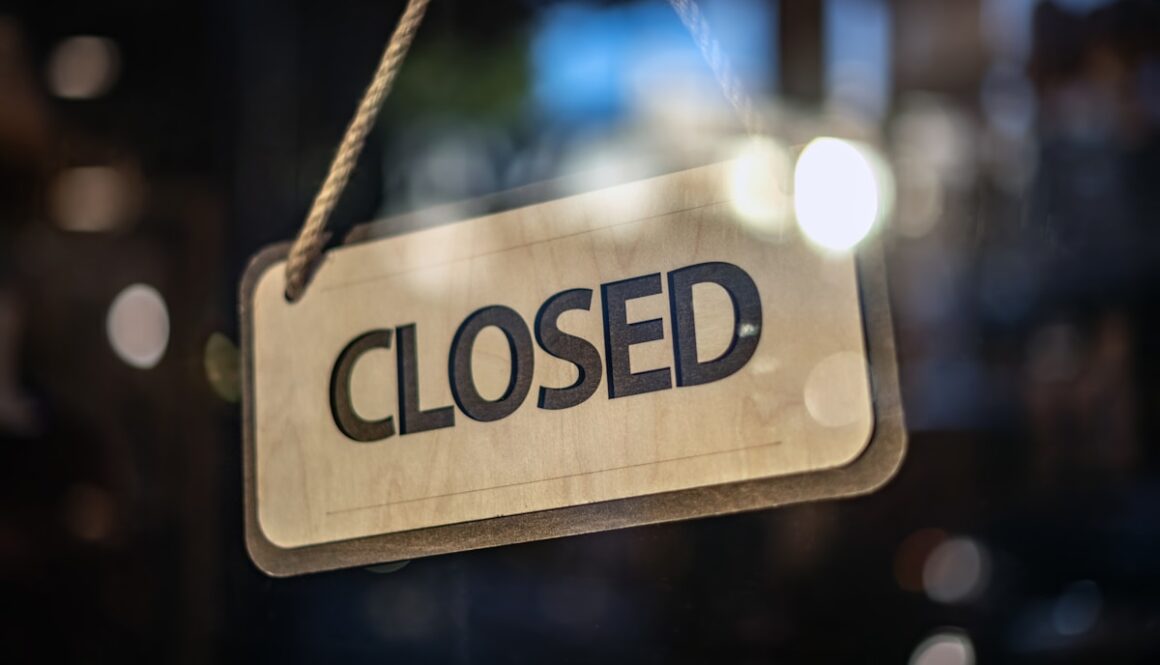 A closed sign hanging from a glass door