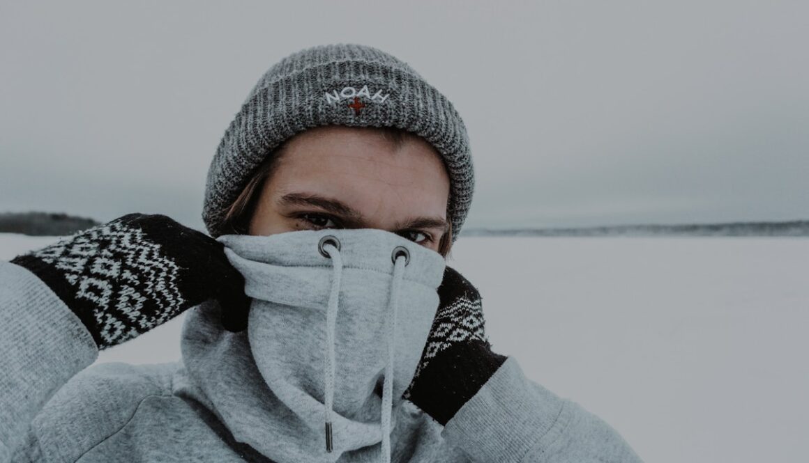 woman in gray knit cap covering her face with gray knit cap
