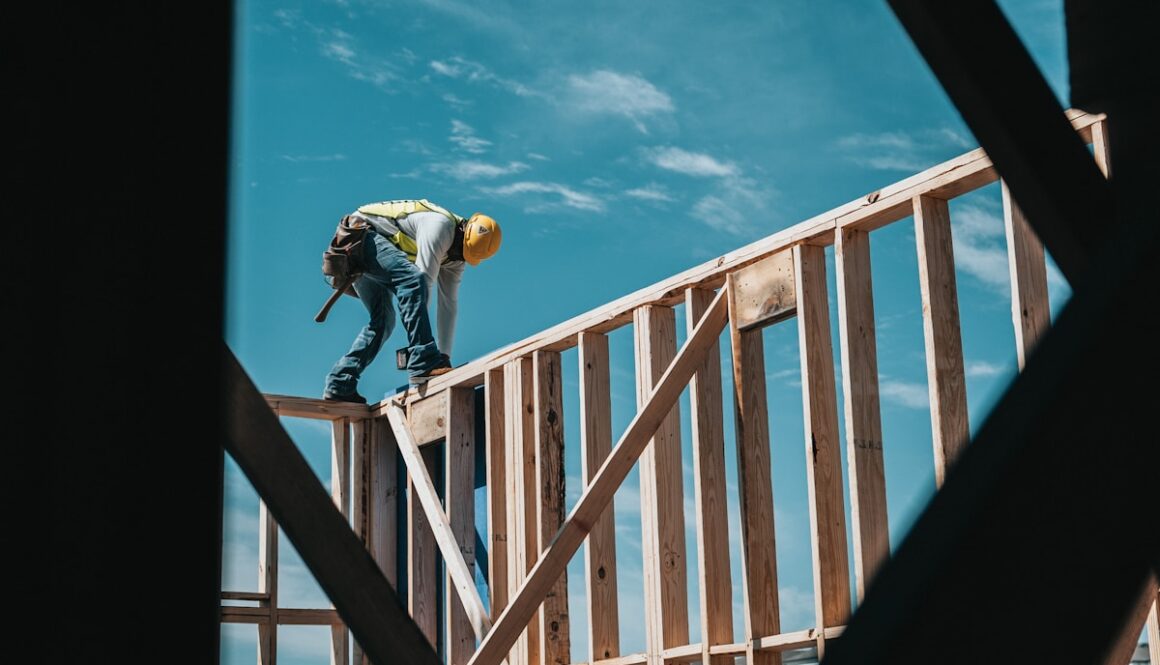 man in yellow shirt and blue denim jeans jumping on brown wooden railings under blue and