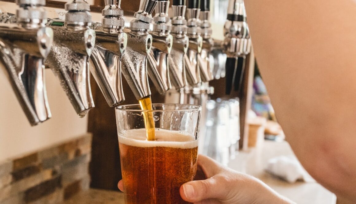 person holding clear drinking glass with brown liquid