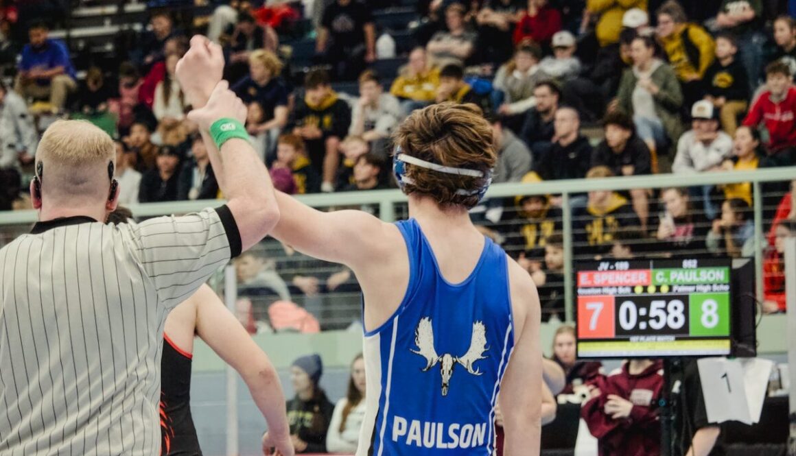 Wrestler's arm raised by referee after match.