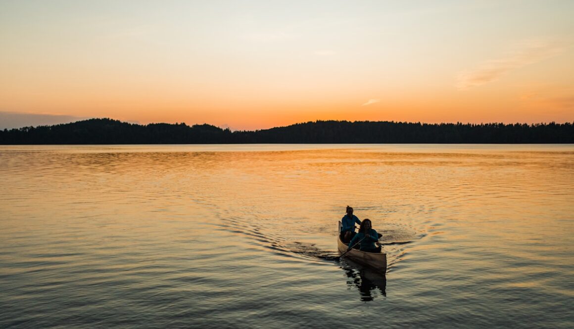 silhouette of 2 people riding on boat during sunset