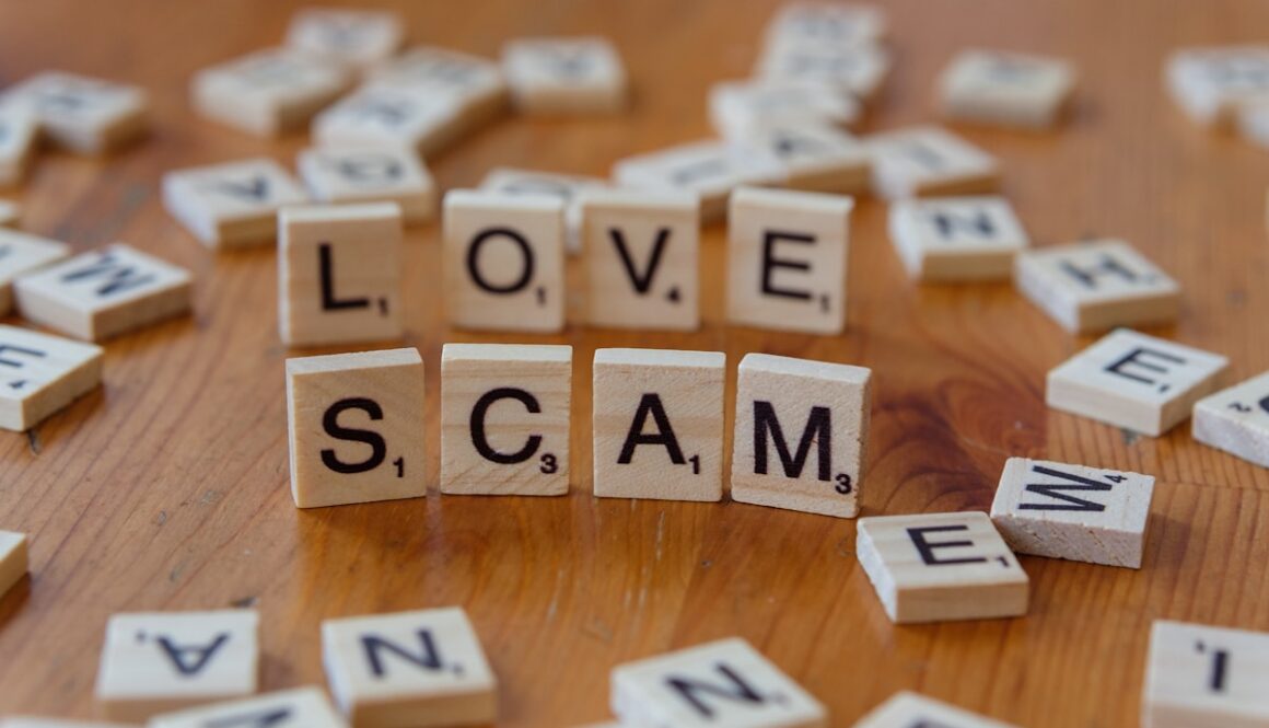 Scrabble letters spelling love scam on a wooden table
