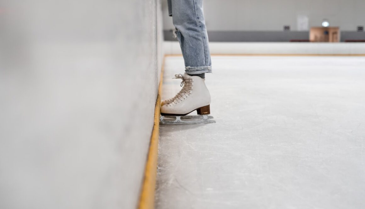person wearing white and gray skate shoes inside ice skating rink