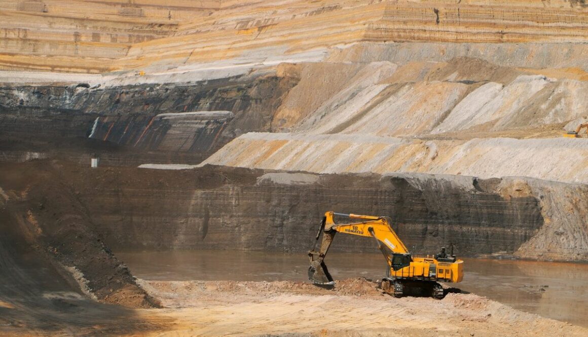 a yellow excavator in a large open pit