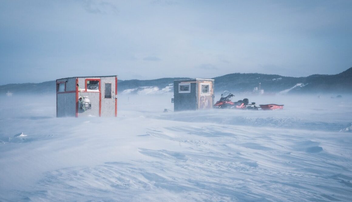 a couple of small buildings sitting in the middle of a snow covered field