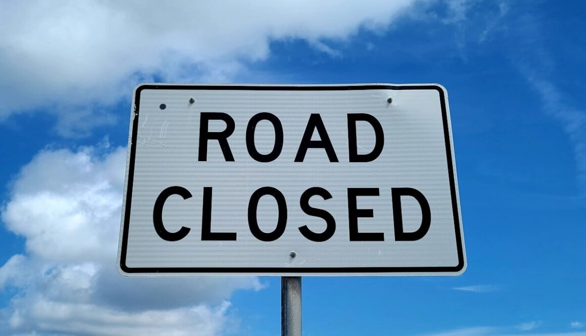 a road closed sign in front of a blue sky