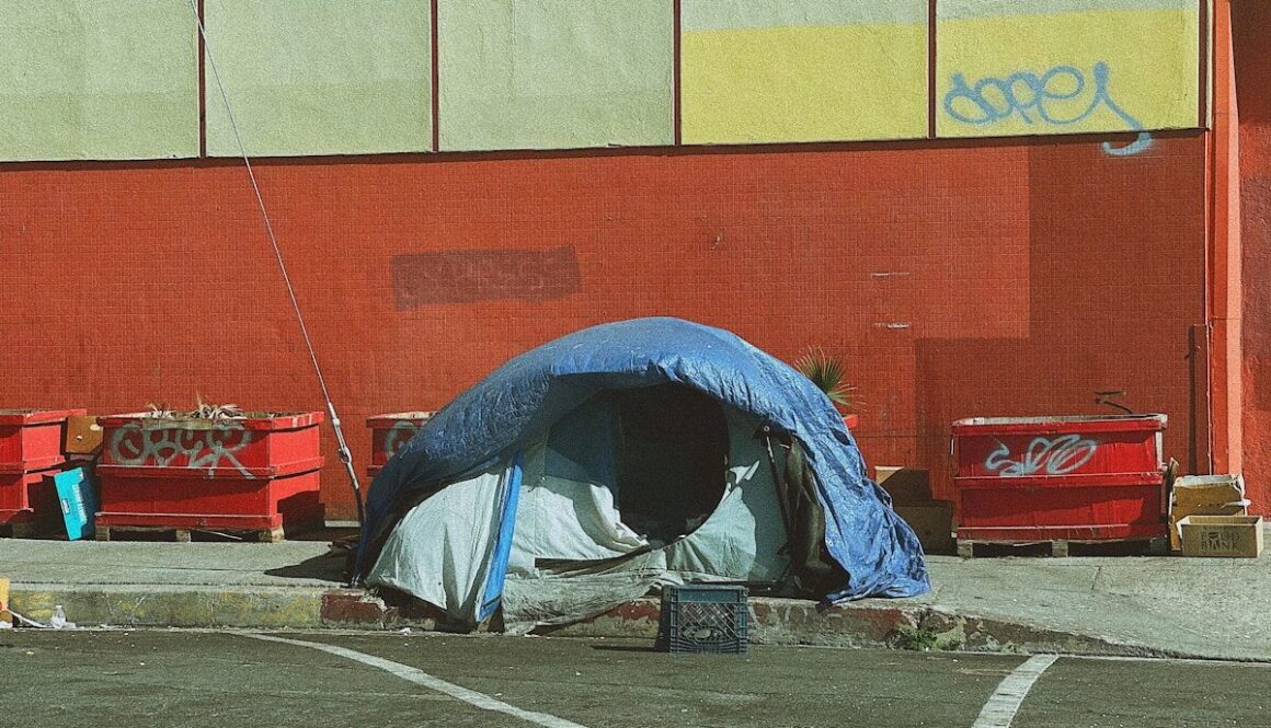 man in blue jacket lying on blue and white tent