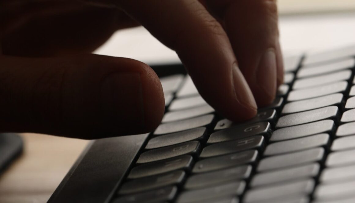 Close-up of a hand typing on a computer keyboard.