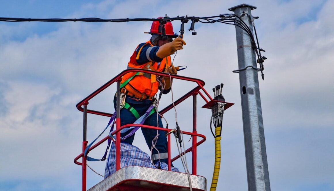 2 men in orange safety helmet riding on red and yellow cable car during daytime