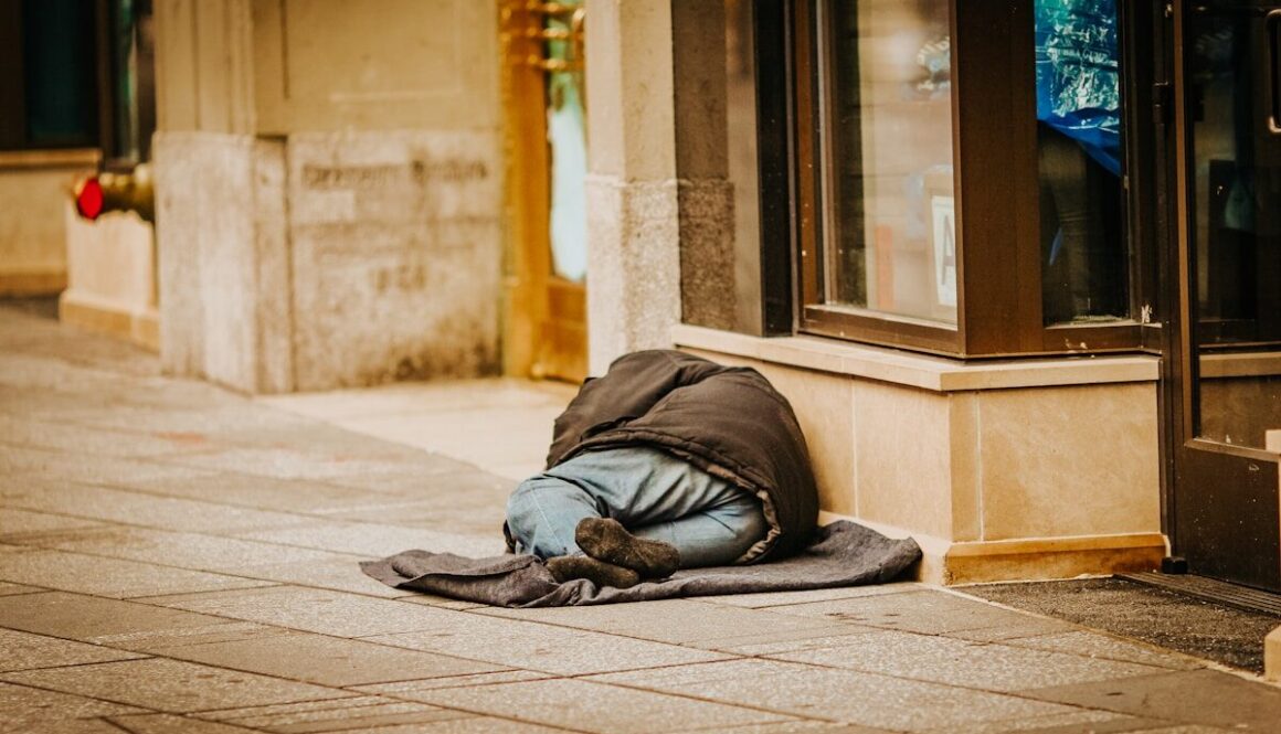 man in gray hoodie lying on gray concrete floor during daytime
