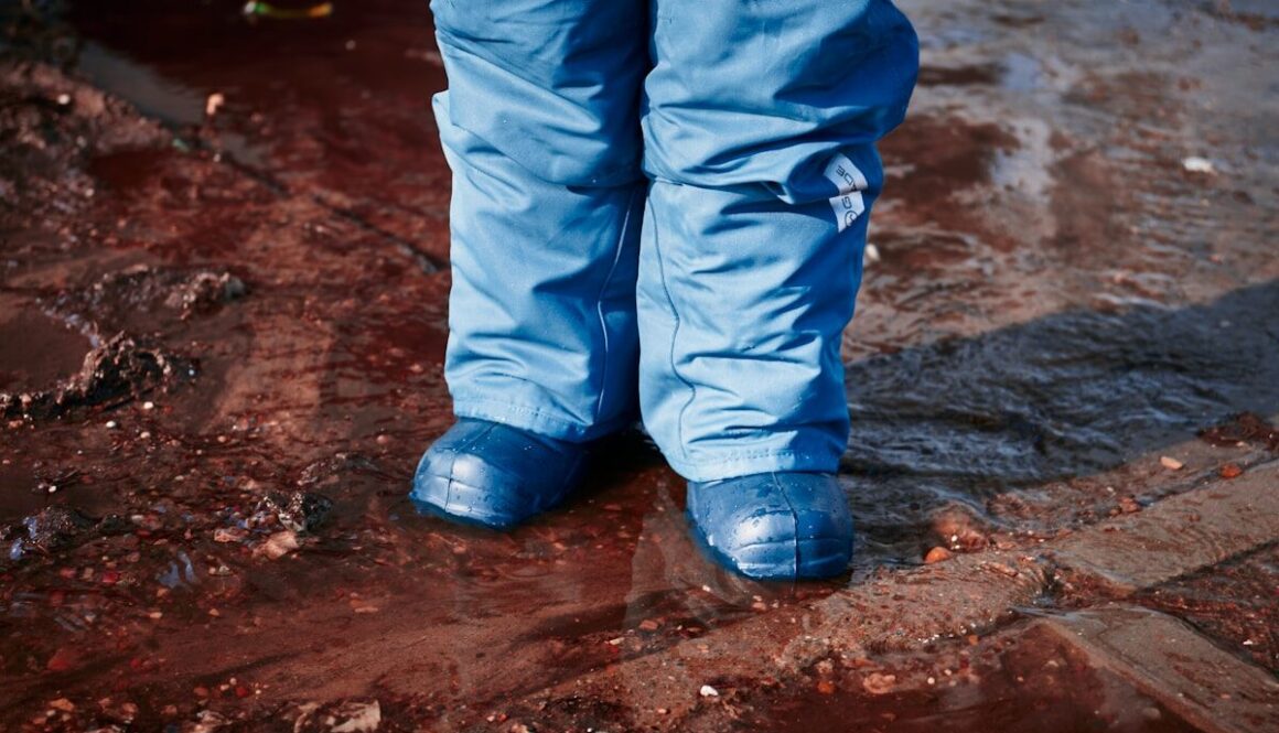 a person standing in a puddle wearing blue rain boots