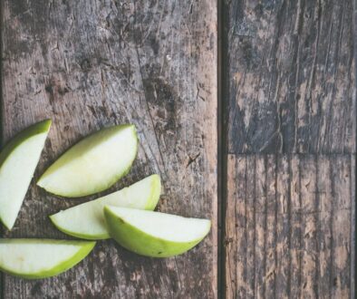 five green apple slices on brown wooden panel