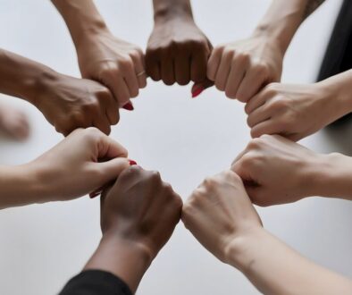People of diverse skin tones fist bumping in a circle.
