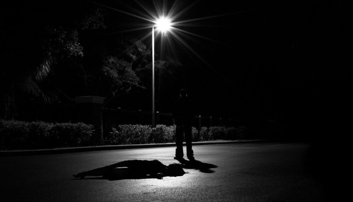 a person laying on the ground under a street light