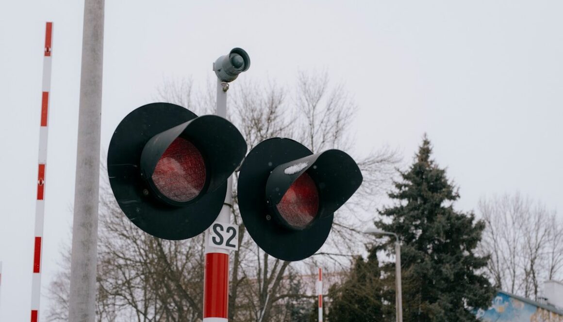 Railway crossing signals display a red warning.