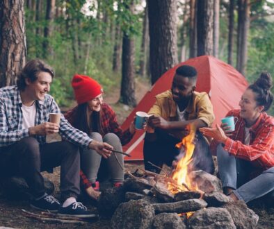 Friends gathered around a campfire in a forest.