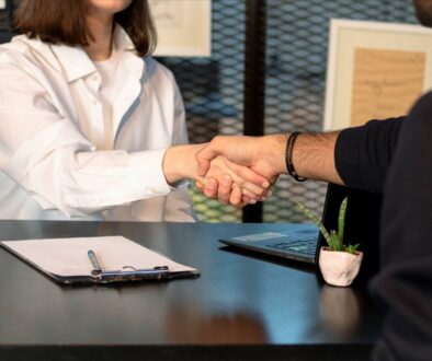 a man and a woman shaking hands in front of a laptop