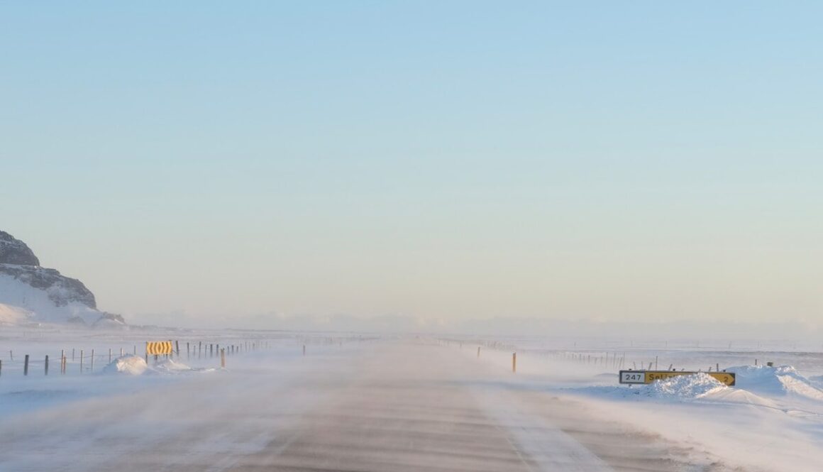 a snow covered road with a mountain in the background
