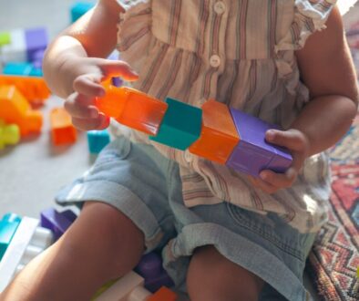 girl in brown button up shirt holding blue and orange plastic toy
