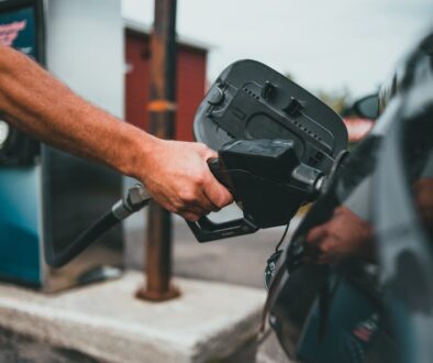 Close-up of a hand holding a nozzle while refueling a car at a gas station.