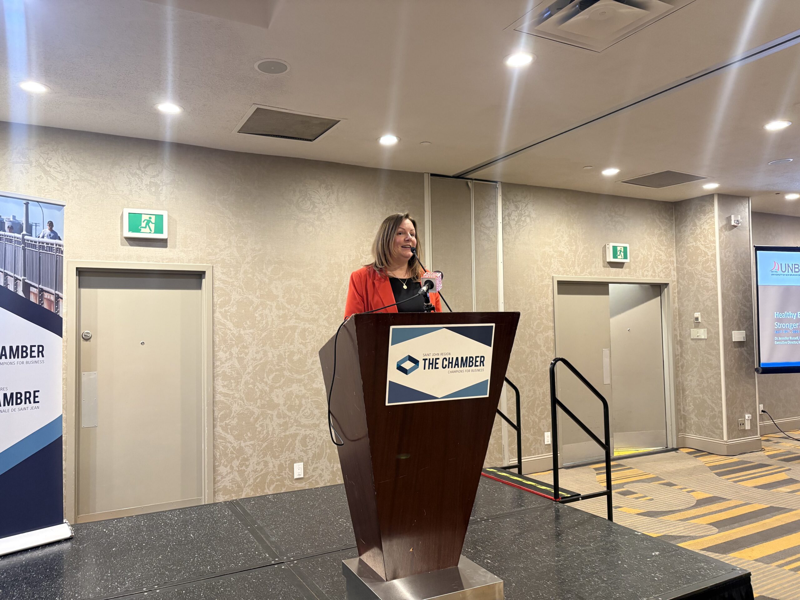 Woman with a red blazer standing in front of a podium 