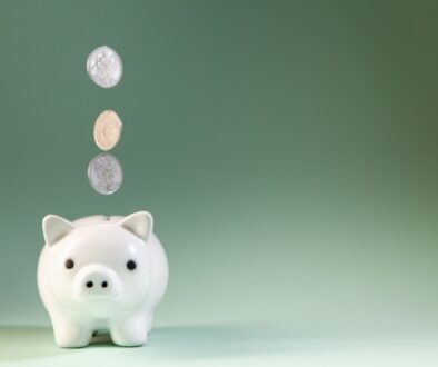 Coins falling into a white piggy bank.