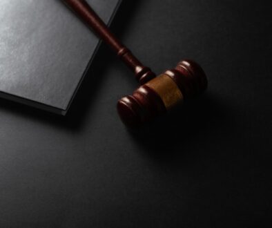 Wooden gavel resting on a dark surface next to book