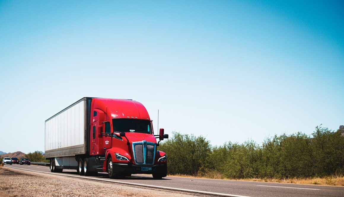 A red semi truck driving down a country road
