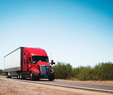 A red semi truck driving down a country road