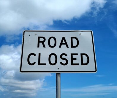 a road closed sign in front of a blue sky