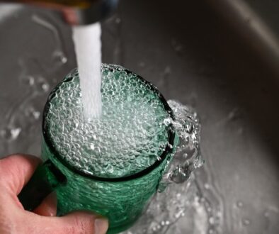 a person's hand is holding a green cup with water coming out of it