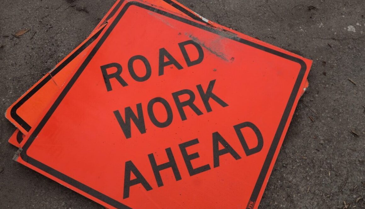 A road work ahead sign laying on the ground
