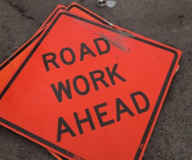 A road work ahead sign laying on the ground